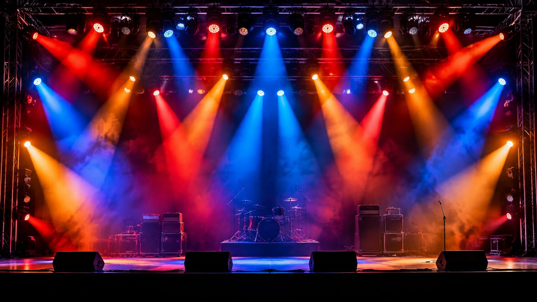 Colorful stage lighting rig glowing above an empty concert stage
